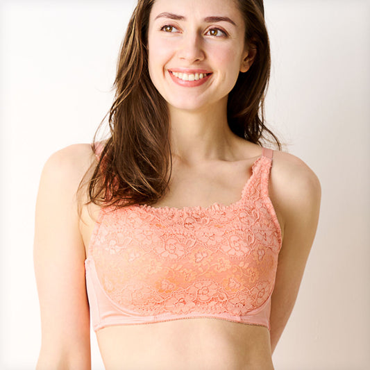 オレンジの胸を小さく見せるブラ、メイン商品画像。黒いレース素材のブラを着用した女性モデルが微笑む正面写真。快適な着心地とエレガントなデザインを強調